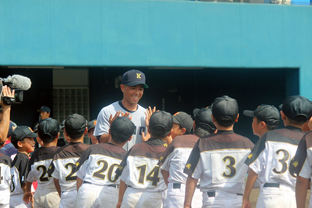 開催地の子供たちにハイタッチで迎えられる照屋主将（環境情報学部4年　沖縄尚学高）