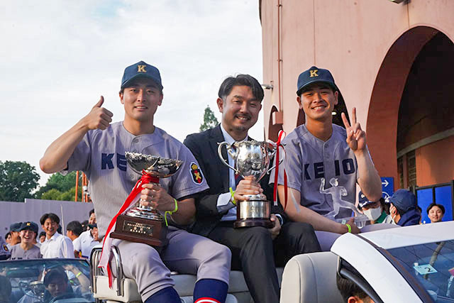 優勝パレードで沿道の声援に応える加藤貴昭部長（中央）と渡辺和大（右）、小原大和（左）の写真